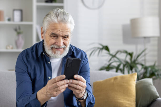 istock Senior man with a charming smile using phone at home 2151010329