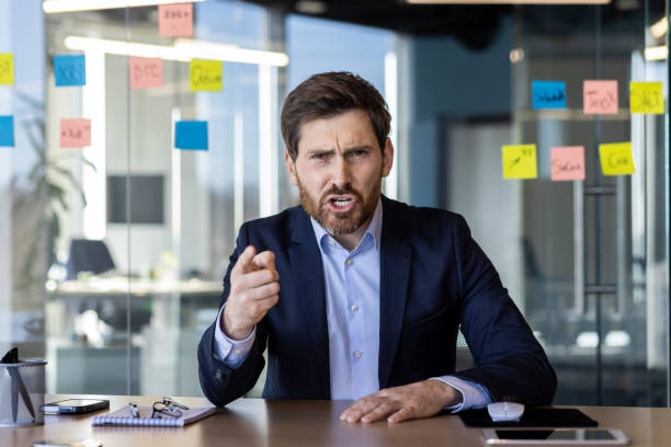 Angry businessman pointing during a video call in office