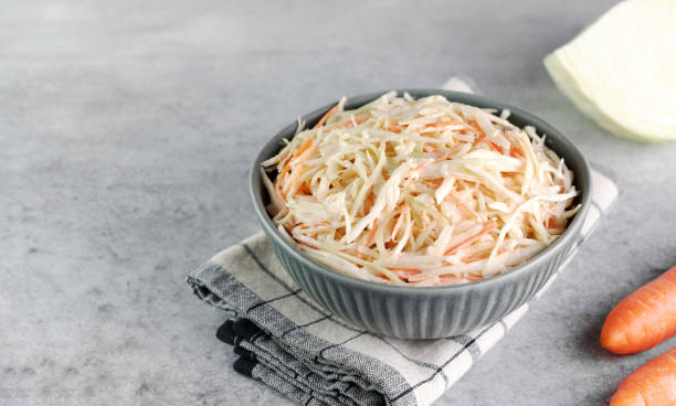 Classic coleslaw salad made with fresh cabbage, carrots and dressing on a white background. American cuisine.
