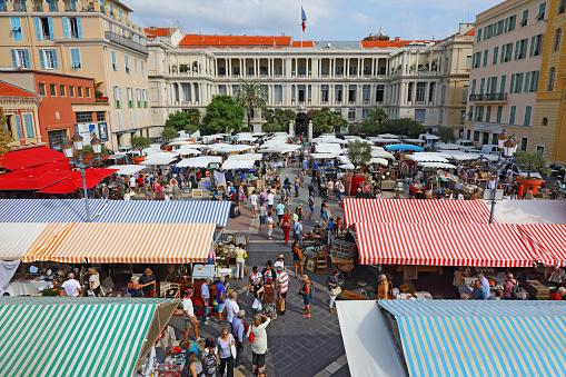 Nice, France - September 17, 2018: The famous Cours Saleya marketplace is surrounded by buildings and their decorative facades. Many people have come here to buy or see something.