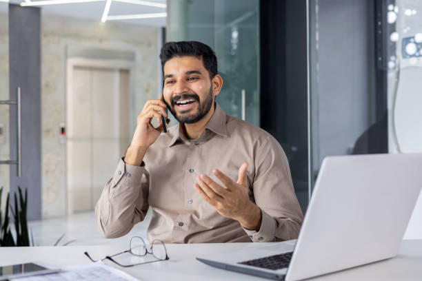 istock Smiling businessman talking on phone at modern office desk 2151013999