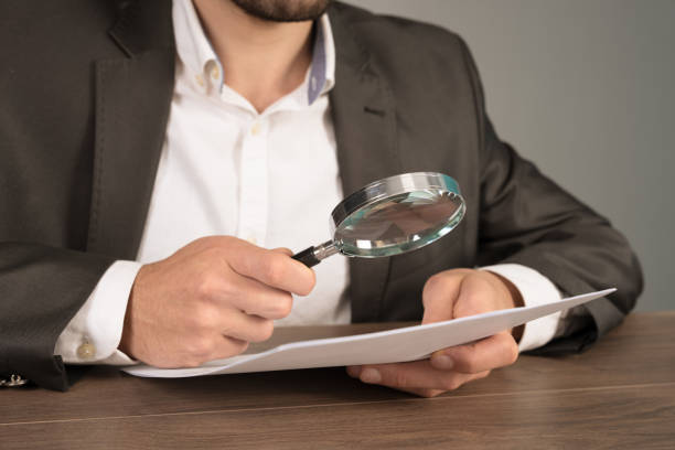 istock A man examines papers with a magnifying glass 2151015279