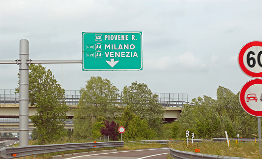 large highway sign with text with the Italian locations of Milan Venice and Piovene
