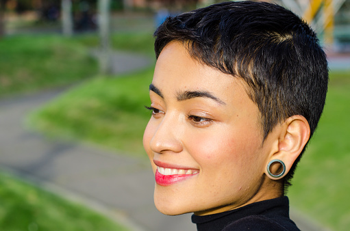 Close-up Portrait of beautiful happy and confident young woman with short hair wearing casual clothes and Stretched ear lobes outdoors in the city