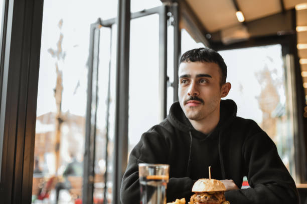 istock Male Enjoying Spicy Burger In Bar 2151019404
