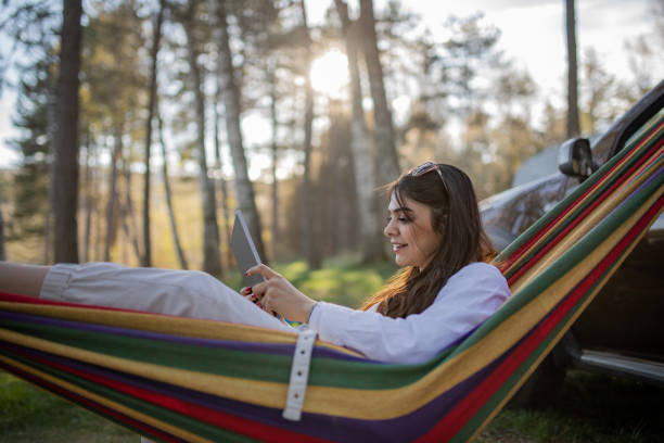 istock Young woman relaxing in a hammock and using digital tablet 2151020044