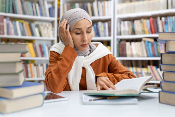 istock Muslim woman studying in library surrounded by books 2151020729