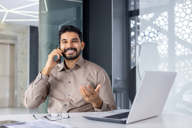 istock Smiling businessman talking on phone in modern office 2151021434
