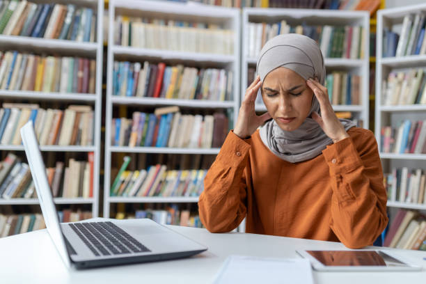 istock Stressed young woman studying in library with laptop 2151028157