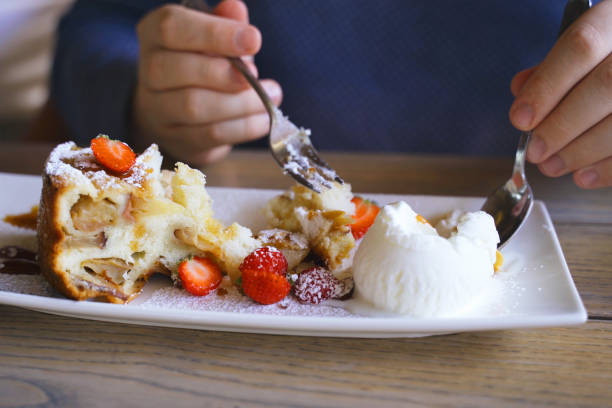 A person is using a fork and knife to cut into a delicious dessert served on a white plate.