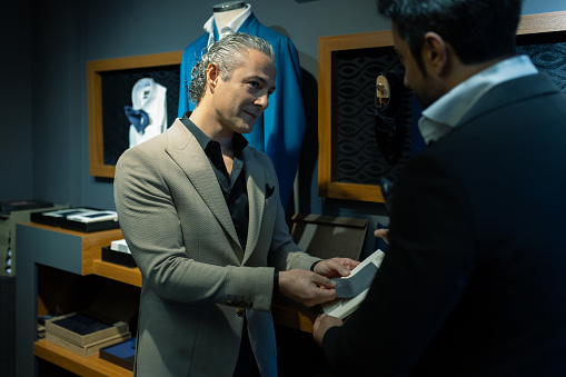 A happy and smiling businessman in a suit inspects fabrics for a new suit at his personal tailor