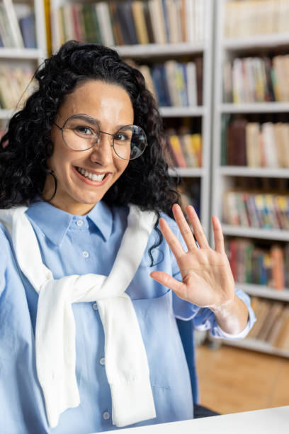 istock Friendly librarian waving hello in a cozy book-filled setting 2151030545
