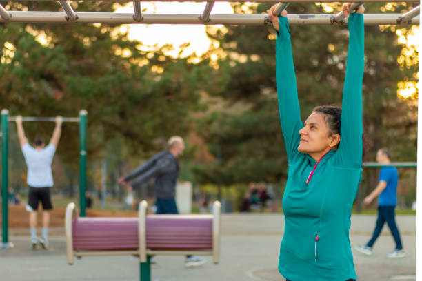 istock Front view of mature woman wearing sports clothes doing pull-ups during a workout on a promenade. 2151030561