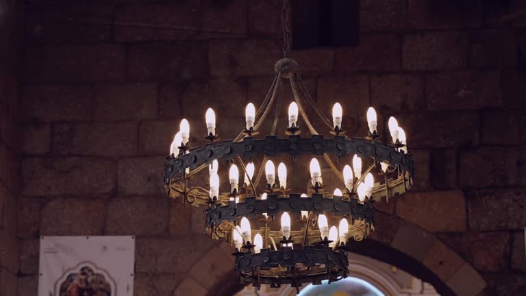 Medieval-style chandelier with lit candles in an old stone chamber