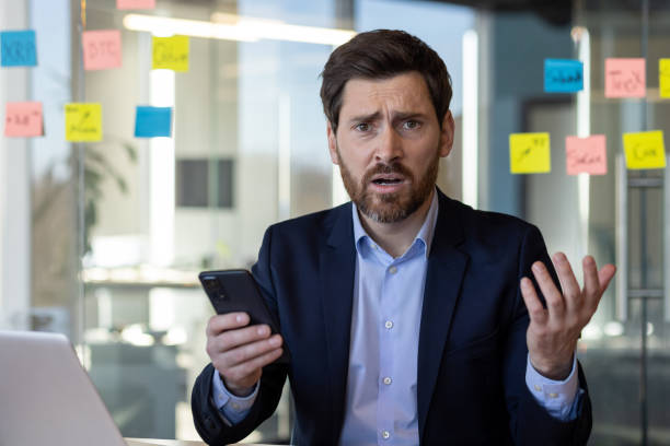 istock Businessman in office perplexed by information on phone 2151032344