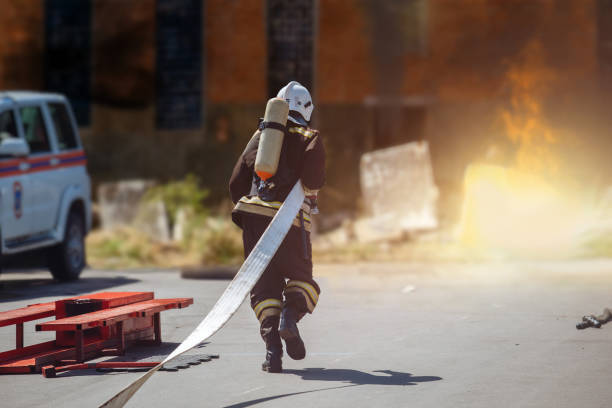 istock Firefighter with hose running to burning industrial building 2151032466