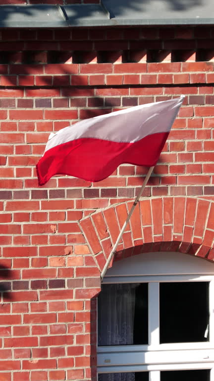 The Polish flag flying on the facade of a red brick tenement house