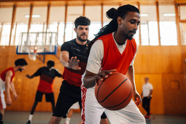 istock Arabic man dribbling ball while playing basketball with his diverse team 2151033699
