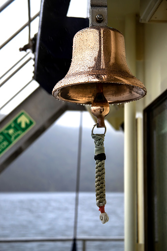 Copper ship bell adorned with raindrops: a vintage symbol of maritime tradition, echoing history and nautical charm. High quality photo