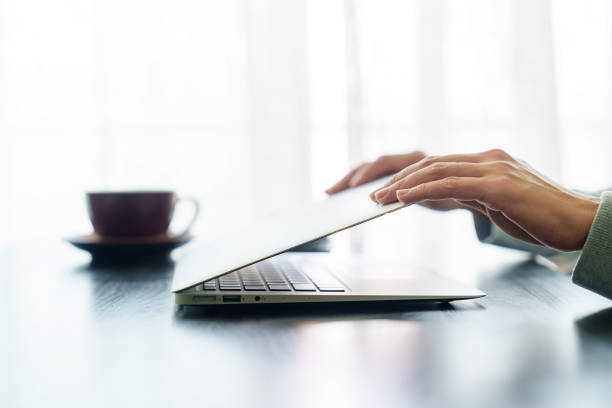 istock The close-up image shows a woman's hands either closing or opening a laptop computer on a table, indicating that she has finished or start using it. 2151037612