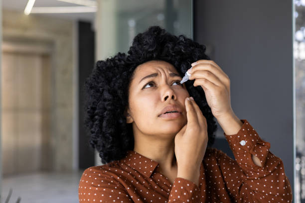 istock Woman in brown polka dot blouse applying eye drops 2151037785