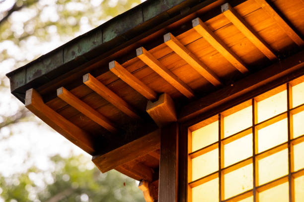 A Traditional Japanese Wooden Lantern glowing in the evening with green trees behind.