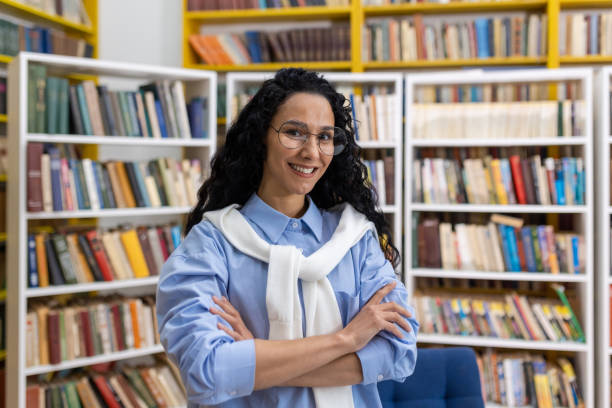 istock Confident female librarian standing among bookshelves 2151043567