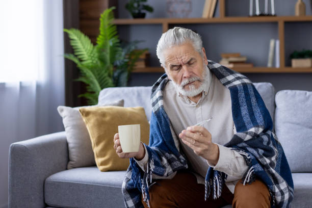 istock Senior man feeling unwell, checking temperature at home 2151044452