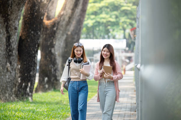 istock University student girl friends with learning book college while walking in campus 2151044787