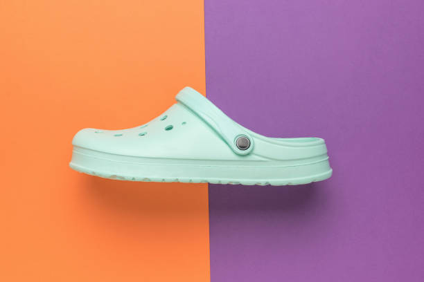 istock Light green women's rubber flip-flops on an orange-purple background. 2151044801