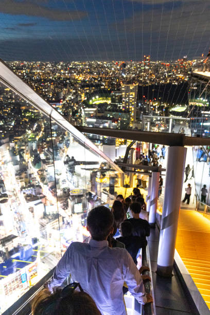Tokyo, Japan - October 6, 2023: A view from a high rise escalator on top a skyscraper looking over the Shibuya ward in Tokyo at night from a high angle view above the street.