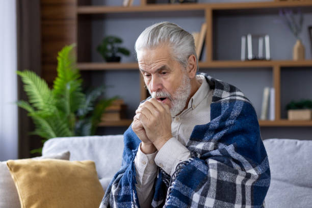 istock Elderly man wrapped in blanket feeling cold at home 2151045676