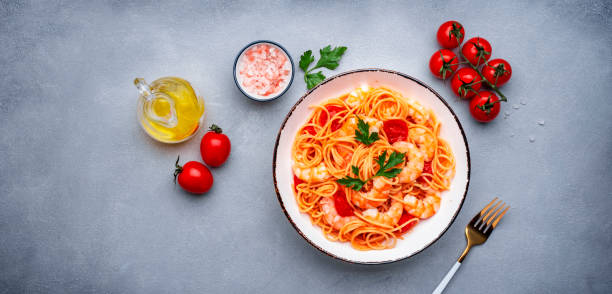 istock Cooked Italian spaghetti pasta with shrimp and tomato sauce, gray table background, top view banner 2151046054