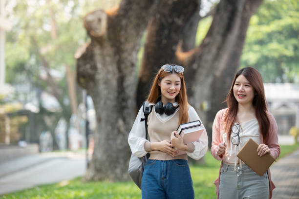 istock University student girl friends with learning book college while walking in campus 2151046147