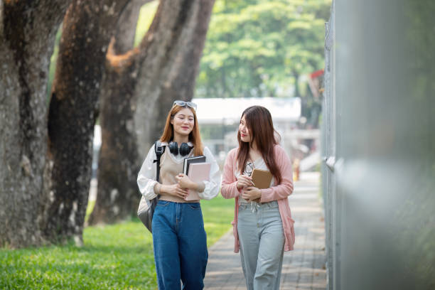 istock University student girl friends with learning book college while walking in campus 2151047451