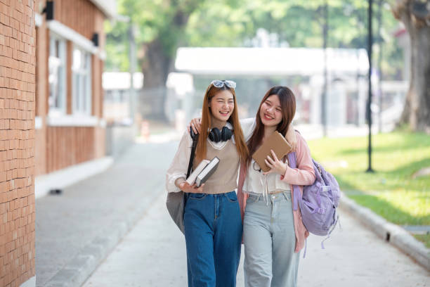 istock University student girl friends with learning book college while walking in campus 2151047469