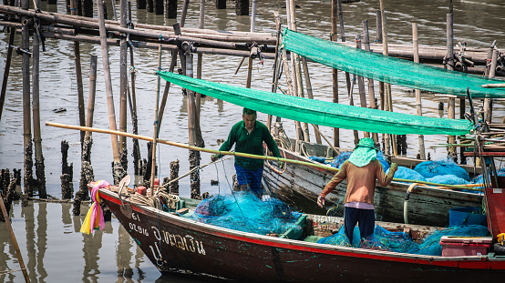 Local fishermen clean their nets on a boat at Phli Pier. Local fishing port in Chonburi Province, Thailand