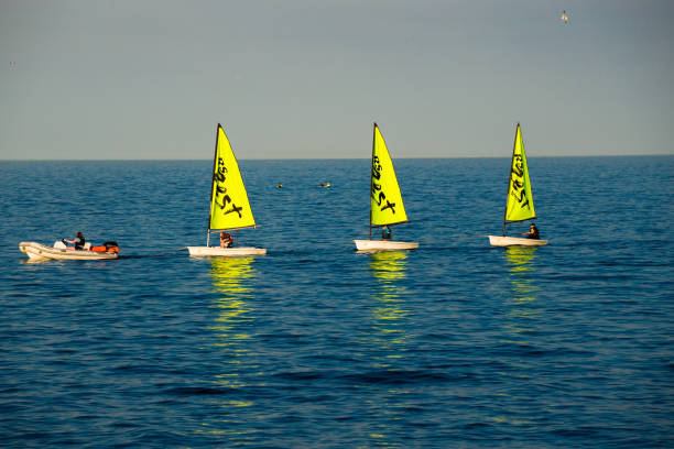 Three bright sailboats at sea. Sports and recreation - navigation on the lake. Boats with a sail