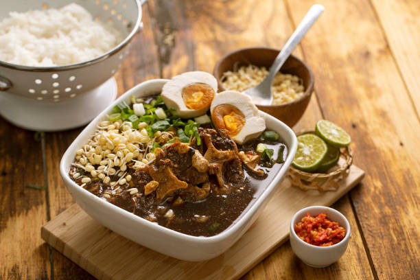 Rawon or  black beef soup , a soup with dark broth and savory taste, served with salted egg and rice