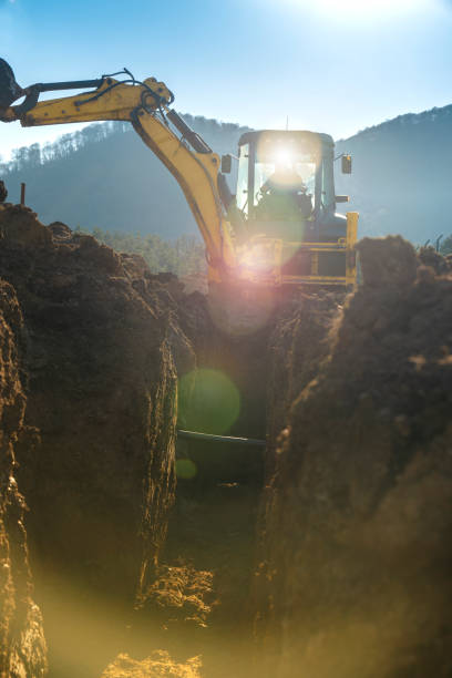 istock Excavators excavate earth on the construction site, view from the ditch, sun light flares, construction in mountains 2151059089