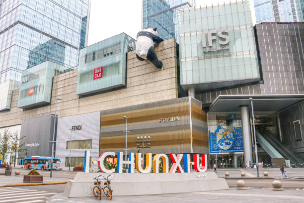 blick auf den haupteingang des einkaufszentrums chengdu international finance square (ifs) und der bürotürme mit einem panda, der darauf klettert, und dem chunxi-straßenschild - chengdu, sichuan, china - chengdu stock-fotos und bilder