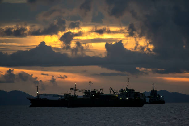 Scenery image of cargo vessels mooring at the sea, under the sunset sky.