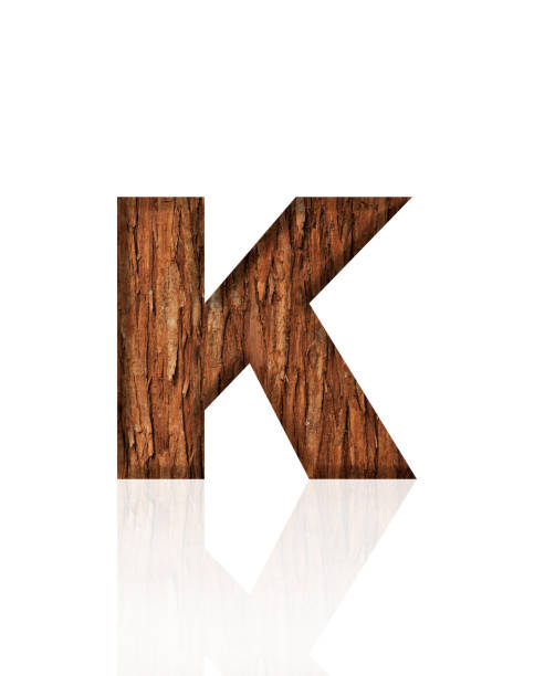 Close-up of three-dimensional tree bark alphabet letter K on white background.