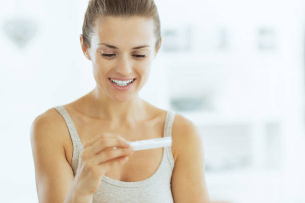 istock Happy young woman looking on pregnancy test in bathroom 2151066518