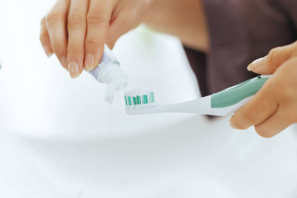 istock Closeup on young woman squeezing toothpaste on toothbrush 2151066522