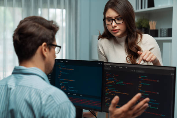 istock Woman standing opposite to man programmer working on desk to discuss. Postulate. 2151068575