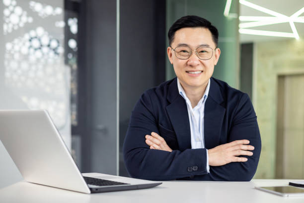 istock Confident Asian businessman smiling at office desk 2151072555