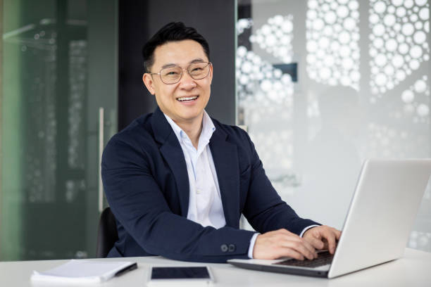 istock Smiling businessman working on laptop in modern office 2151072774