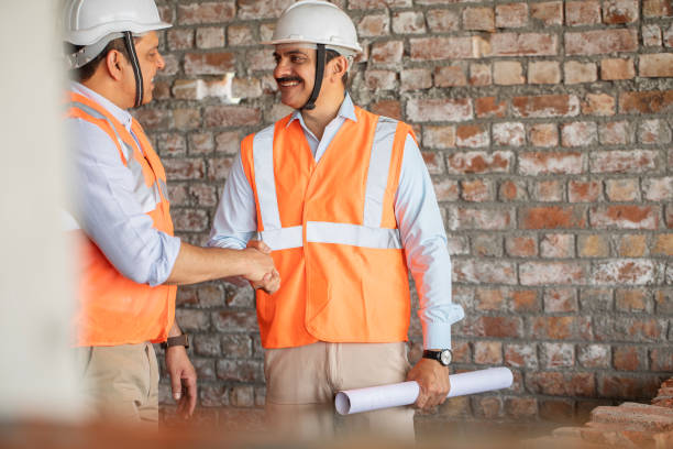 istock Male coworkers shaking hands at construction site 2151073094