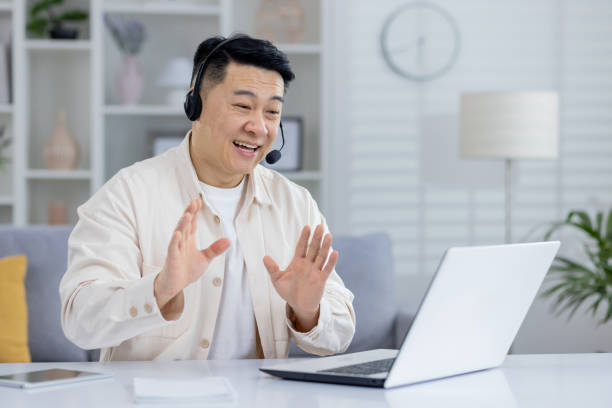 istock Cheerful senior man with headset using laptop at home 2151073136